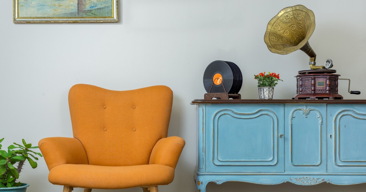 A retro, orange armchair sits next to a light blue, vintage hall table with a gramophone and records on top.