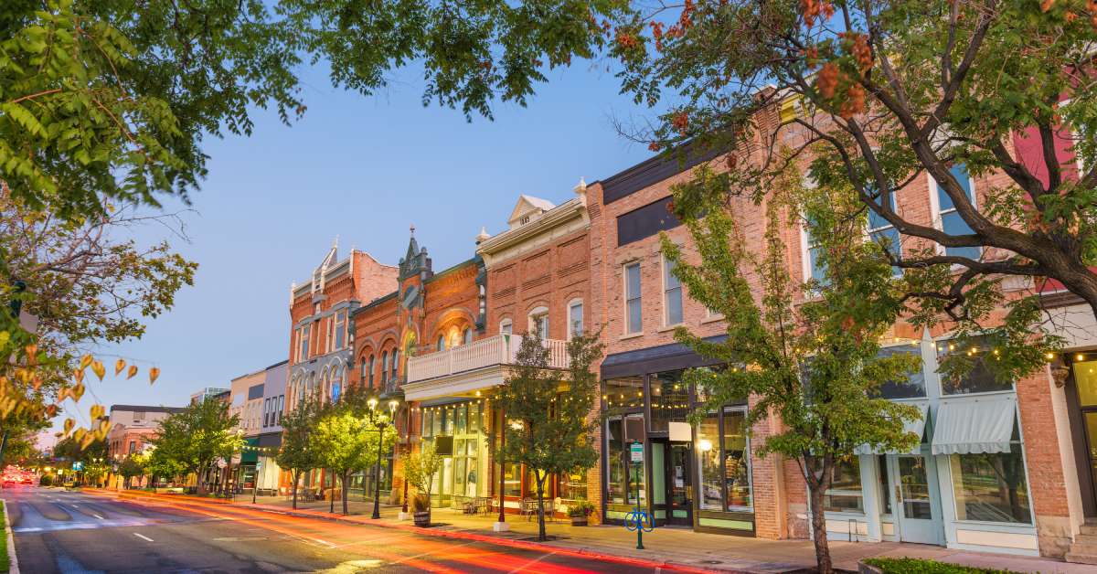 A street view of a downtown shopping area where the buildings have brick faces. There is a red streak of light darting across.